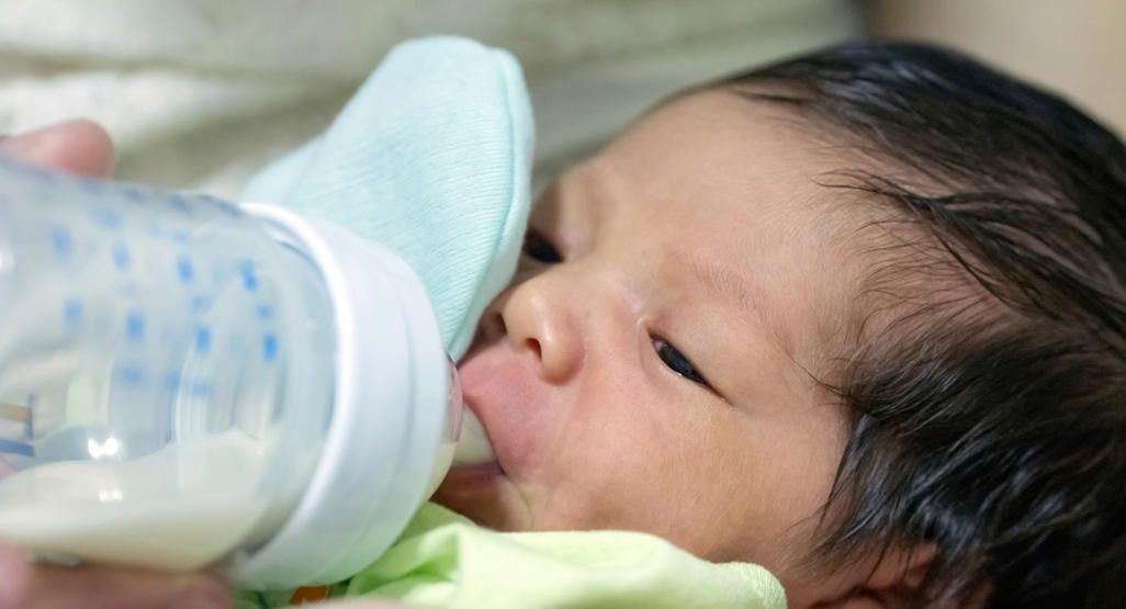 Newborn baby vomiting milk during feeding